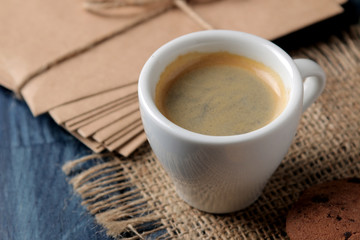 Natural espresso coffee in a ceramic coffee cup and cookies on a blue wooden table.