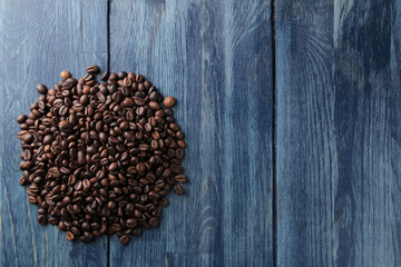 a handful of roasted coffee beans on a blue wooden table. place for text. view from above