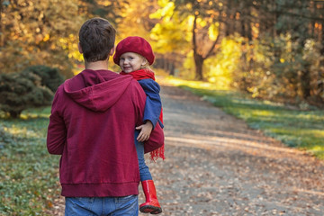 Father hugs daughter in autumn day. Back view, copy space.
