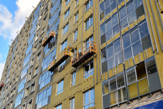 Workers install glass and panels on the facade of building