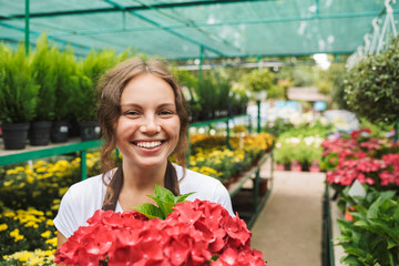 Happy young woman working in a greenhouse