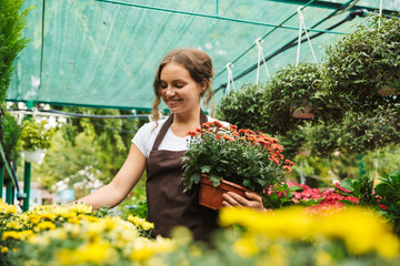 Florist woman 20s working in greenhouse over plants