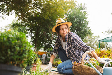 Woman gardener with water can working near flowers in greenhouse