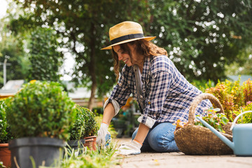 Woman gardener with water can working near flowers in greenhouse