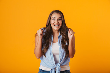 Excited young woman posing isolated over yellow wall background.