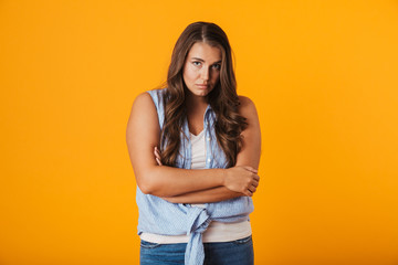 Upset young woman standing isolated over yellow
