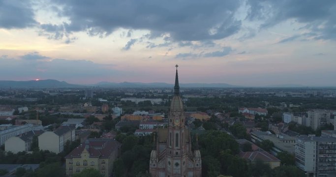 Aerial shot of catholic church in Budapest at sunset with cityscape and sun in view