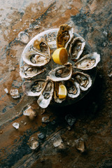 top view of oysters, ice and lemon on grungy tabletop