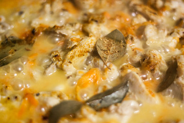 Stew chicken pieces in a pan with vegetables and spices. the sauce is boiling. selective focus.