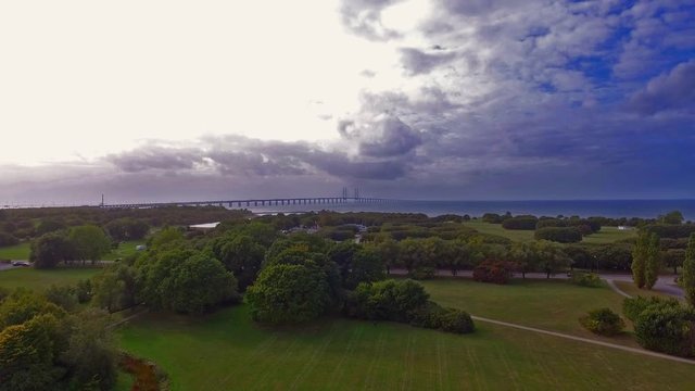 Aerial shot from Hammars park of Oresundsbron with Sibbarps camping and a cloudy sky in 4k.