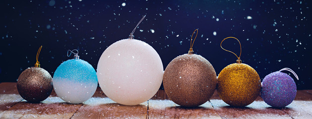 Christmas balls on a wooden table with snow