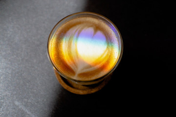 Top view of coffee cup with heart shape latte art foam on black  table,LGBT flag effect.
