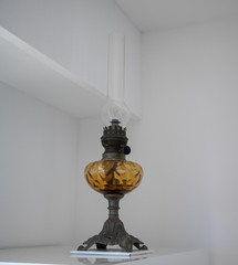 Ancienne lampe à pétrole en verre soufflé acier et mèche coton dans un salon - antiquité...