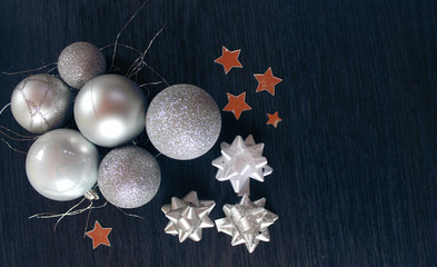 Silver christmas balls with ribbons and stars on black background