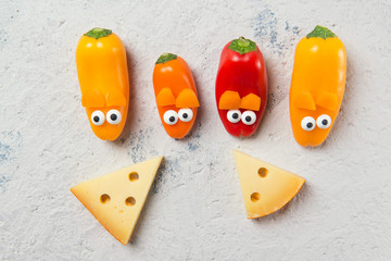 Obraz premium Colorful sweet mini peppers in the shape of mouses and pieces of cheese, stone table, top view, snack for kids idea