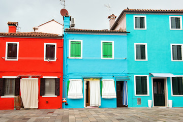 Fototapeta na wymiar Fronts of the bright red, blue and turquoise houses on the island of Burano, Venice, Italy