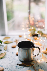 Cup with tea near the window with autumn leaves and cookies