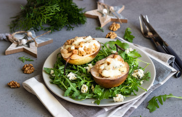 Baked pears with gorgonzola, chicken, walnuts and mozzarella with arugula on a grey plate. Grey slate, stone or concrete table. Healthy salad or snack for Christmas or New Year. Copy space.