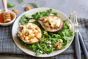 Baked pears with gorgonzola, chicken, walnuts and mozzarella with arugula on a grey plate. Grey slate, stone or concrete table. Healthy salad or snack for Christmas or New Year. Copy space.