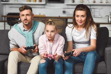 concentrated family sitting on sofa and playing video game