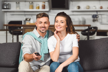 husband and wife sitting on sofa and watching tv together