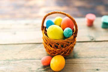 Colored easter eggs in a basket on a wooden background