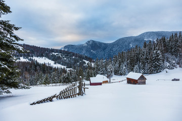 wooden house in a perfect snowy winter landscape. Snow covered rural and forest landscape.