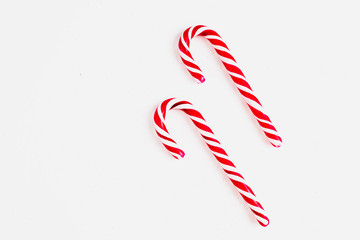 Candy canes on a white surface, top view, place for text