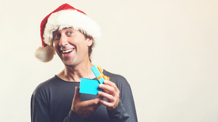 Santa christmas man opening gift box present. Amazing man in Santa hat isolated on white, with copy space. Christmas holidays. Happy man enjoying Christmas time. Christmas shopping and sales concept.