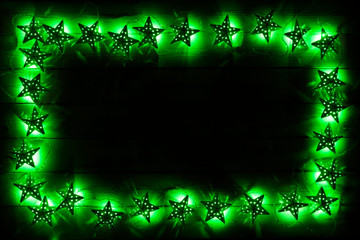 Green star christams lights on a dark wooden background