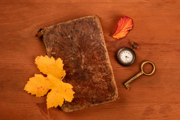 Naklejka na ściany i meble A photo of an old notebook with a pocket watch, a vintage key, and autumn leaves., shot from the top on a dark rustic wooden background with a place for text