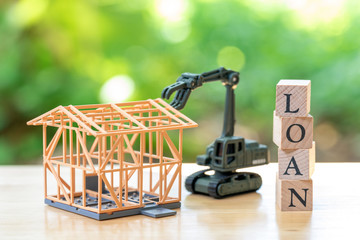Fototapeta premium Construction worker A model house model is placed with wood word LOAN using as background business concept and finance concept with copy space