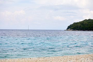 Obraz premium Sailing yacht in the Mediterranean. Concept of travel and active lifestyle. Stone beach and warm sea