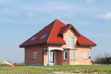 Fototapeta na wymiar Jaslo, Poland - 7 8 2018: Modern design of a small single-family house located in a rural area. Designing buildings and landscape. New home for people. Red metal roof. Energy saving and greenhouse eff