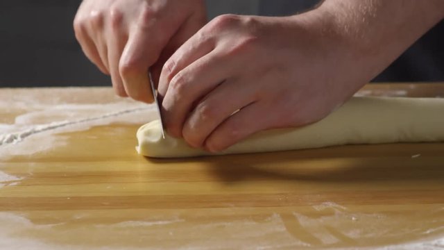 Close up PAN shot of unrecognizable male cook forming and cutting dough