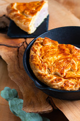 Food concept homemade pork pie or meat pie in cast Iron Skillet and stone plate on wooden background