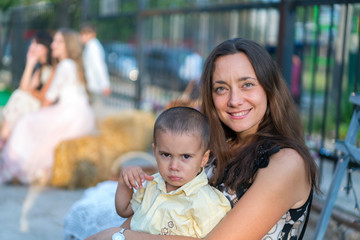 Obraz premium Mom holds a child in her arms. A happy family. Young mother holding her baby in her arms and stroked my mother's child litso. Portret mother and little son.
