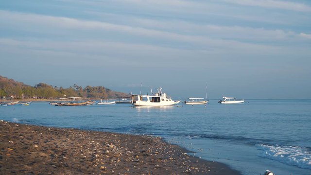 Black sand beach and small white and colorful traditional boats in calm sea water. Shot with Sony a7s and Atomos Ninja Flame on sunny summer day.