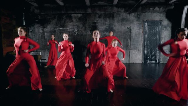 Modern ballet performed by seven dancers. Girls in red dresses synchronously perform dance elements