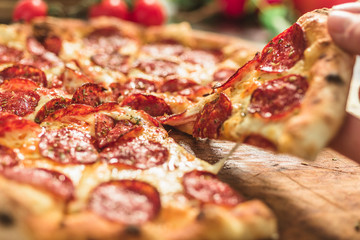 Hot pizza slice with melting cheese on a rustic wooden table.