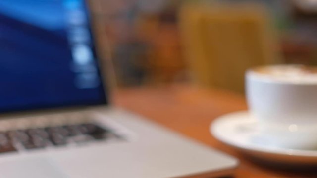 Blurry, defocus, out focus of a cup of cappuccino coffee with laptop on table. Royalty high quality free stock image of capuccino coffee with laptop for working in a coffee shop. Blur background