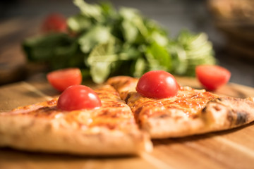 Hot pizza slice with melting cheese on a rustic wooden table.