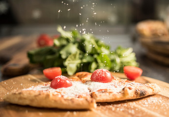 Hot pizza slice with melting cheese on a rustic wooden table.