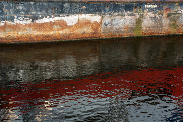 Background: rusty side of the boat and its reflection in the water