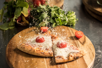Hot pizza slice with melting cheese on a rustic wooden table.