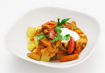 Dish of vegetables and meat on a white background