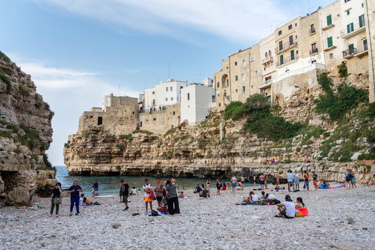 POLIGNANO A MARE, ITALY - JULY 6 2018: Tourist looking from view in historic center to lovely beach Lama Monachile, Adriatic Sea, Apulia, Bari province on July 6, 2018 in Polignano a Mare, Italy.