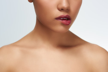 Young woman studio standing isolated in white wall touching neck looking camera cocky close-up bites lips