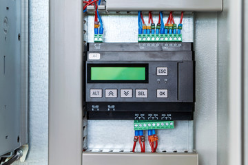Controller or logic control relay in the electrical Cabinet on the circuit Board. The device has a liquid crystal display. The wires are connected using terminal blocks. Modern automation.