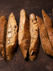 Close View Of Biscotti - Traditional Italian Almond Dessert On Dark Copper Background. Cookies Arranged On The Center In Photo With Copy Space. Top View, Selective Focus, Vertical Composition.